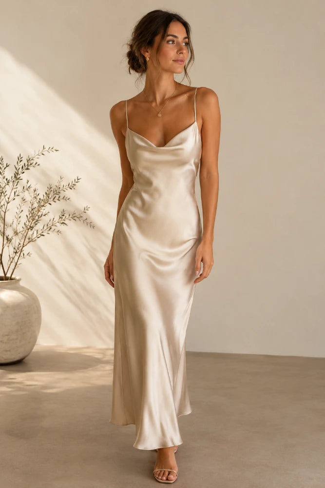 Woman wearing a long champagne satin slip dress with spaghetti straps in soft natural light