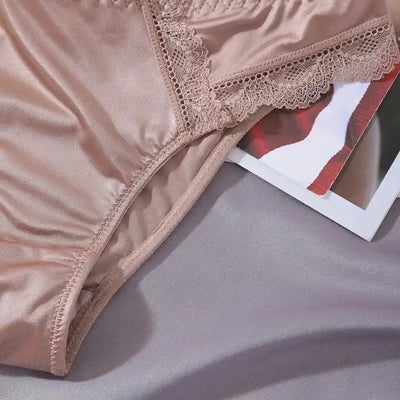 Detail flat lay of nude satin bikini panties showing lace side trim and gusset lining