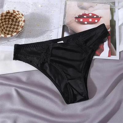 Single black satin bikini panty with tonal lace trim laid flat on a gray surface
