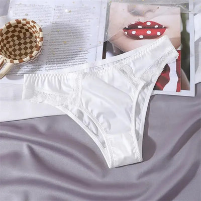Single white satin bikini panty with white lace trim laid flat on a gray surface