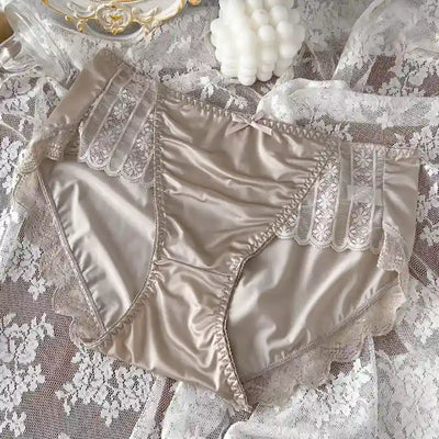 Taupe satin high-rise panties with vertical lace panels and bow detail, lace fabric background