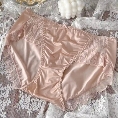 Light pink satin panties with vertical lace panels and scalloped trim, flat lay on lace fabric