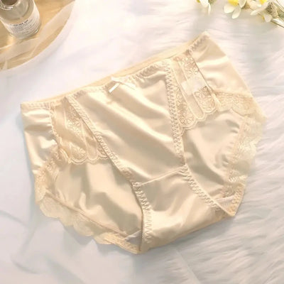 Cream satin panties with scalloped lace trim and center bow, laid on white textured surface