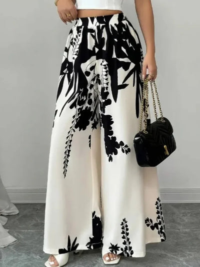 Front close-up of high-waisted ivory wide-leg pants with bold black floral print and black chain bag