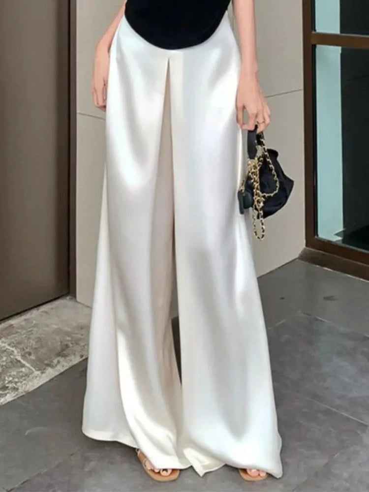 White satin wide-leg pants with center pleat worn with black top and sandals