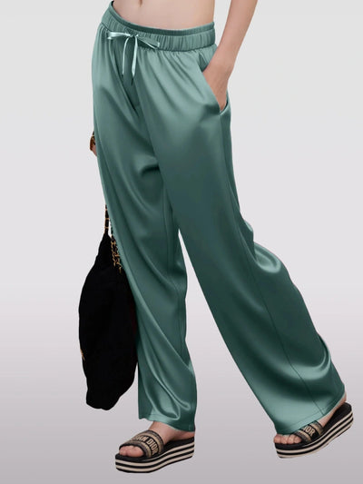 Side view of teal wide-leg satin pants with Dior platform sandals and chain bag