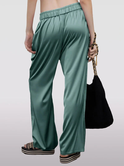 Back view of teal wide-leg satin drawstring pants with Dior slides and chain bag