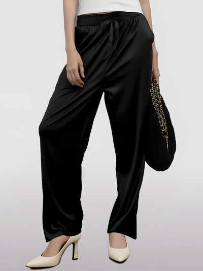 Front view of black wide-leg satin drawstring pants with white heels and chain bag