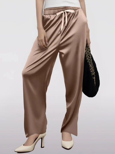 Front view of champagne wide-leg satin drawstring pants styled with white heels