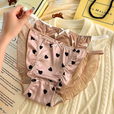 Hand holding pink and chocolate brown heart print satin panties with lace sides