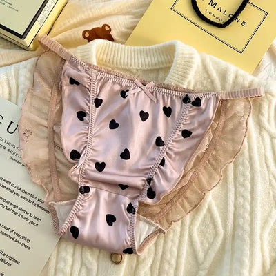 Pink satin panties with black hearts and blush lace ruffled side panels close up