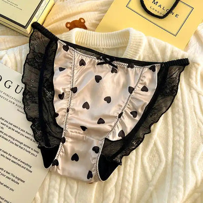 White satin panties with black hearts and bold black lace ruffle panels close up