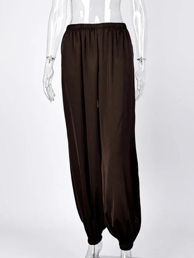 Front view of dark brown wide-leg satin pants with elastic waist and gathered ankle cuffs on mannequin