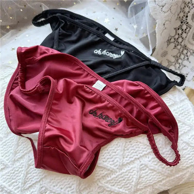 Burgundy and black satin bikini briefs with embroidered script heart detail flat lay
