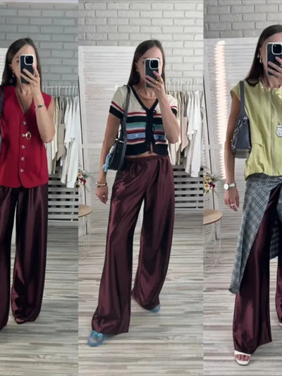 Three mirror selfies showing burgundy wide-leg satin pants styled with a red vest, striped knit cardigan, and yellow sleeveless top