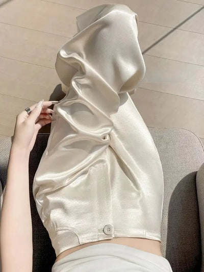 Champagne wide-leg satin pants draped and gathered on a woman's lap showing fabric texture