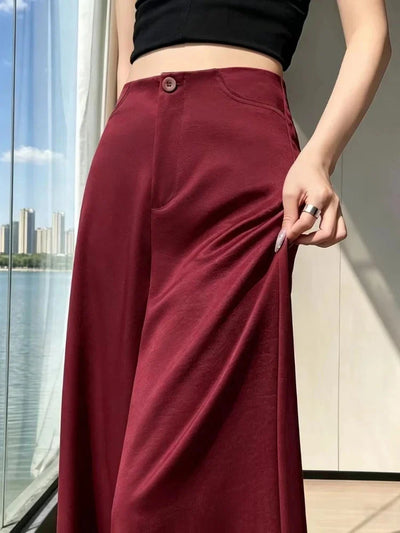 Close-up of burgundy high-waisted wide-leg satin pants showing button closure and hip pocket