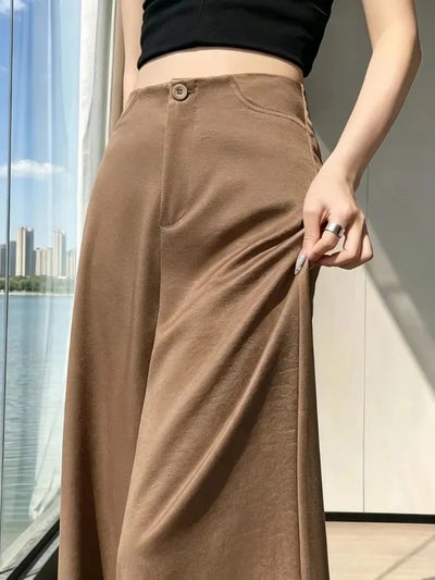 Close-up of camel high-waisted wide-leg satin pants showing button closure and hip pocket detail