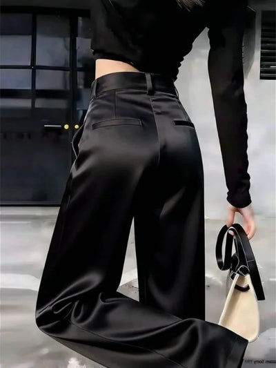 Close-up back view of black high-rise wide-leg pants showing waistband belt loops and welt pocket detailing