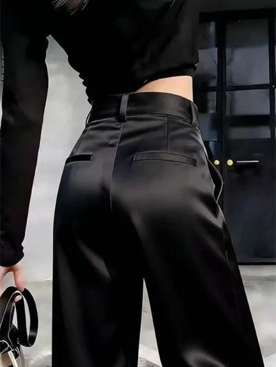 Angled close-up of black wide-leg pants back rise and welt pocket detail, model leaning forward