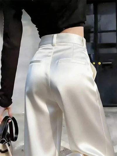 Low-angle rear view of ivory satin wide-leg pants showing fluid fabric movement at the hem