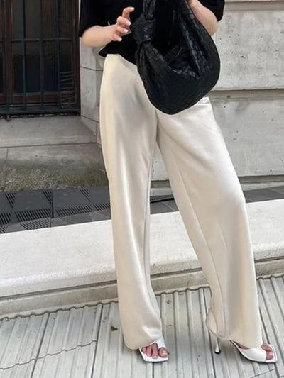 Ivory fluid wide-leg pants worn with white heels and a black top, outdoor street setting