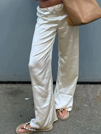 Ivory satin wide-leg pants with ruched elastic waist, styled with pearl sandals and a tan tote