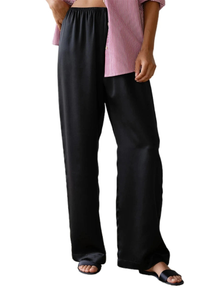 Woman wearing black flared wide-leg satin pants with gray knit cardigan and white block-toe shoes on a crosswalk