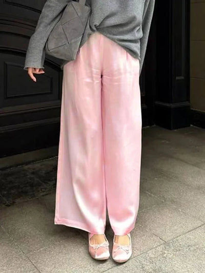 Pink high-shine wide-leg satin pants styled with gray knit and ballet flats outdoors