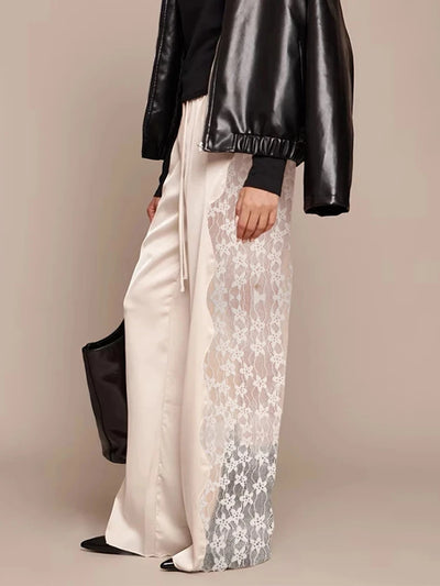 Side view of ivory lace-panel wide-leg pants styled with black leather bomber jacket and clutch