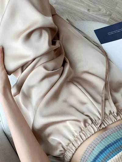 Close-up of beige satin wide-leg pants fabric showing glossy fluid drape and elastic waistband drawstring detail