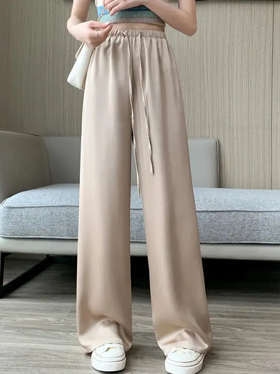 Full-length front view of beige drawstring wide-leg pants styled with white sneakers and a striped crop top