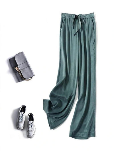 Full-length sage green fluid wide-leg pants styled with white sneakers and a gray crossbody bag