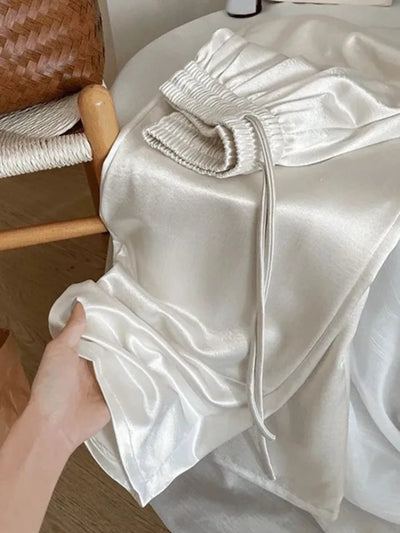 Close-up of smocked elastic waistband and drawstring tie on white glossy satin pants