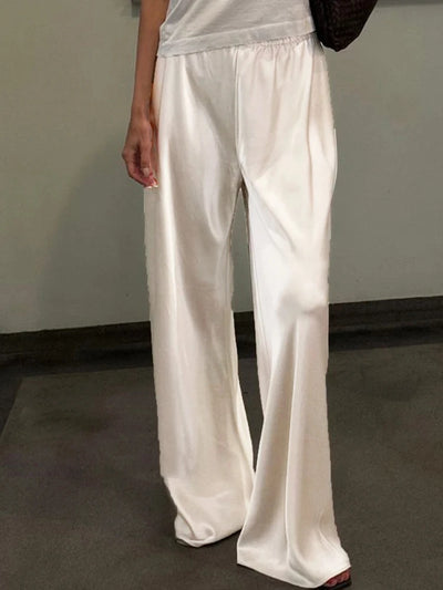 Woman wearing ivory wide-leg satin pants with elastic waist, full-length front view indoors