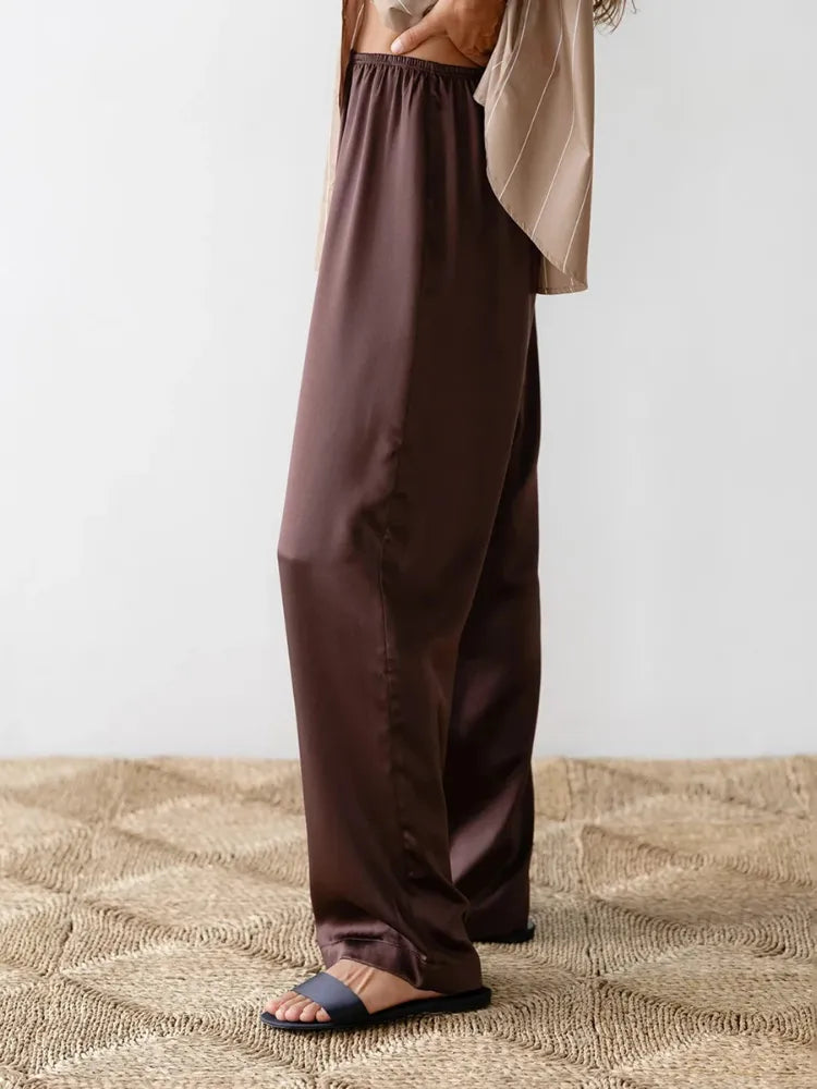 Side view of chocolate wide-leg satin pants with elastic waist and slide sandals