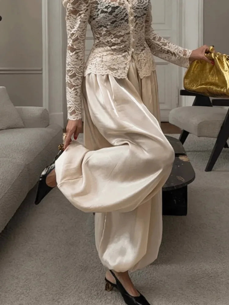 Champagne satin wide-leg pants with lace-trim waist worn with matching ivory lace top and black heels