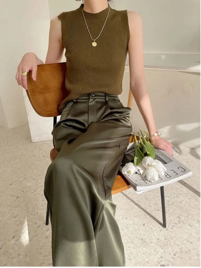 Woman seated in olive high-waisted wide-leg satin pants and matching ribbed tank top holding white tulips