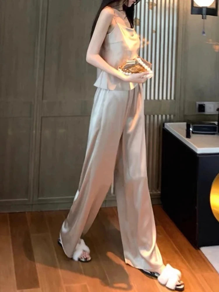 Woman wearing champagne satin cami top and wide-leg floor-length pants set with heeled sandals