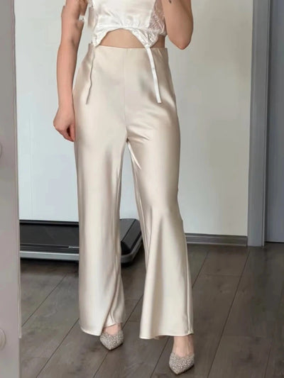 Champagne high-waist flared satin pants front view on model with pointed heels