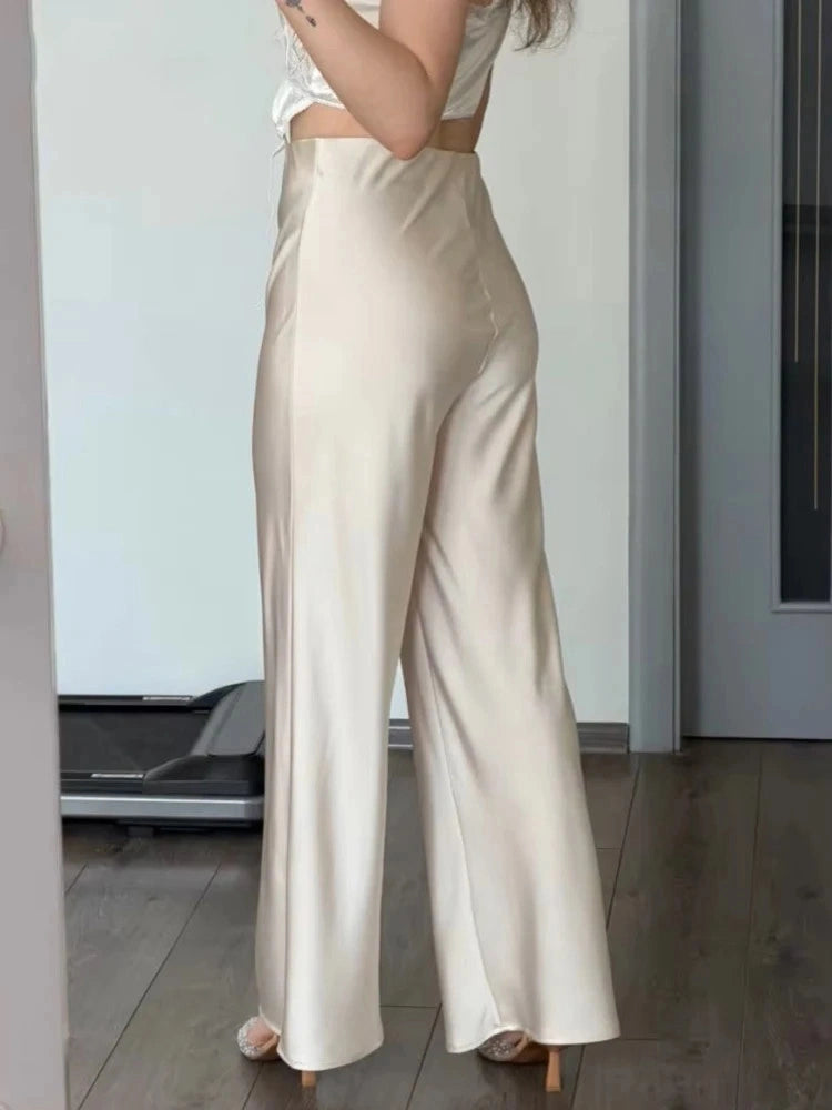 Champagne high-waist flared satin pants front view on model with pointed heels