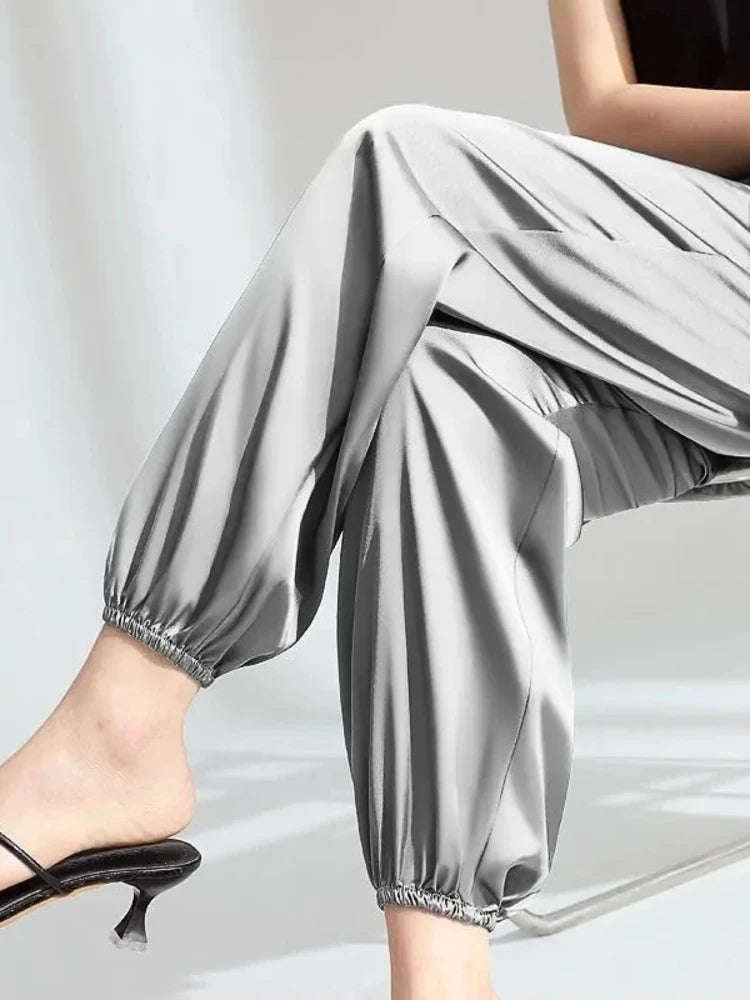 Gray high-shine balloon satin pants with elastic ankle cuffs, styled with black pointed-toe heeled mules