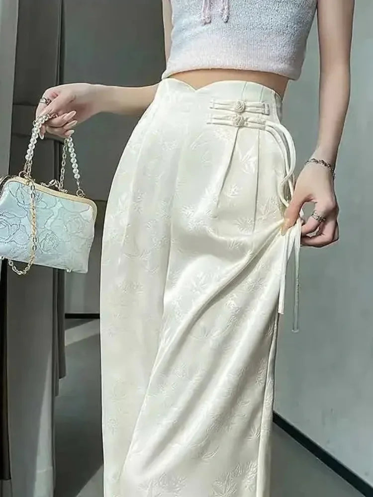 Cream high-waist wide-leg satin pants with frog-button closures and ribbon ties, front view standing