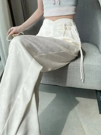 Cream wide-leg floor-length pants with sweetheart waistband and knotted frog buttons, seated view