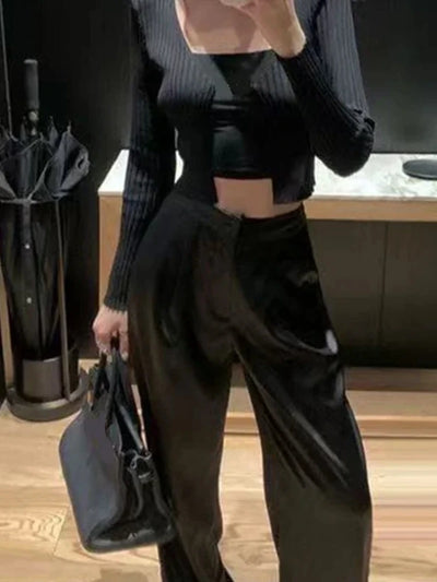 Front view of black fluid wide-leg pants styled with cropped ribbed top and designer bag