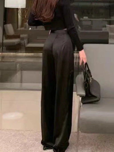 Back view of black floor-length wide-leg pants with high-rise waist and glossy finish