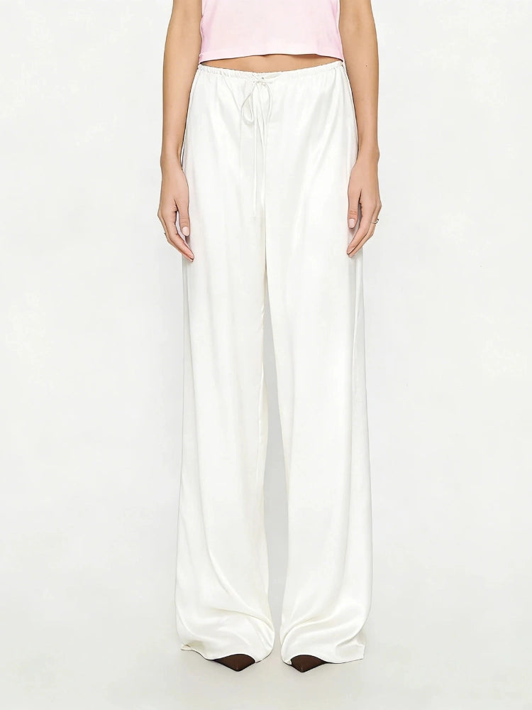 Woman wearing ivory high-shine wide-leg satin pants with a white drawstring waistband