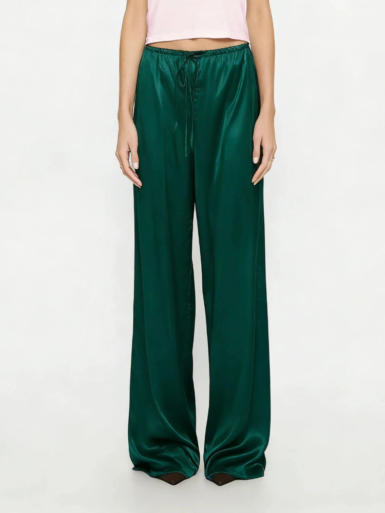 Woman wearing emerald green wide-leg satin drawstring pants with a pink crop top