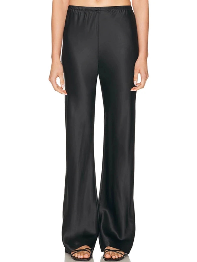 Woman wearing black low-rise wide-leg satin pants with strappy black heeled sandals
