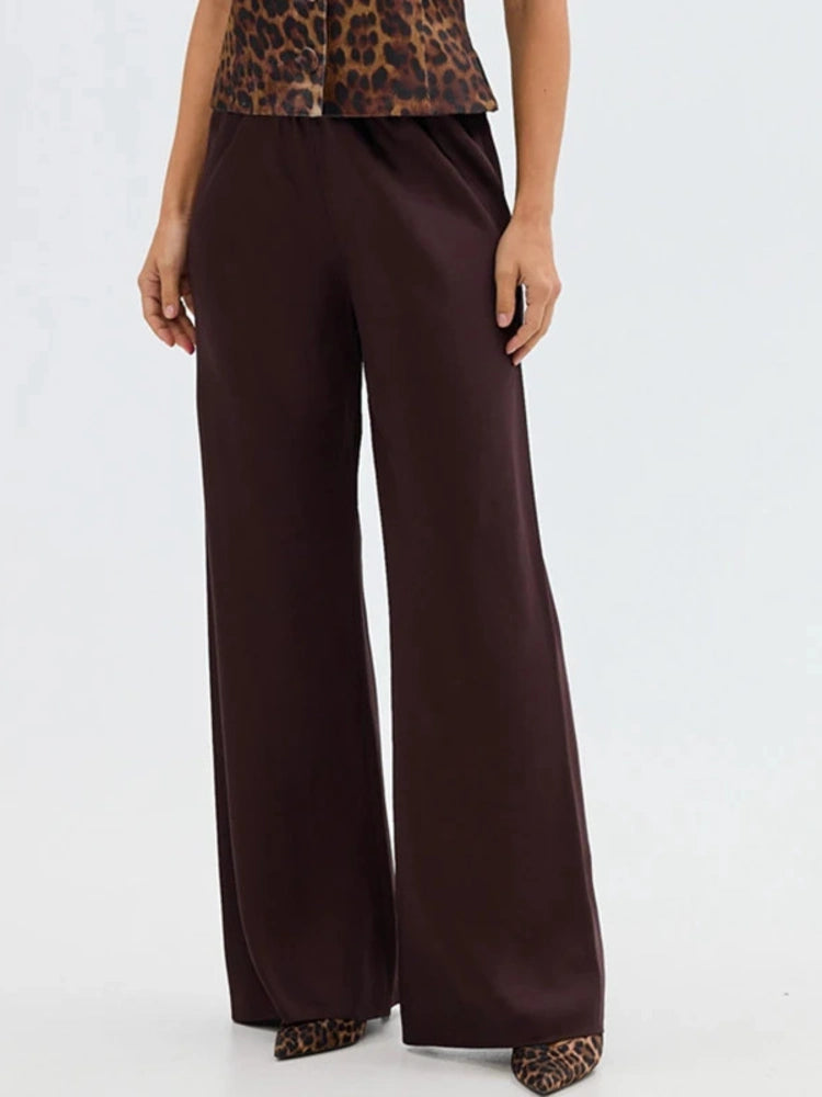 Woman wearing dark chocolate high-waist wide-leg satin pants with leopard print top and heels